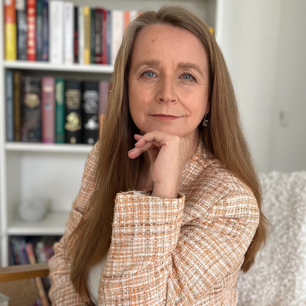 Inhaberin der Praxis mit langen, blonden Haaren und freundlichem Lächeln, im Freien fotografiert.