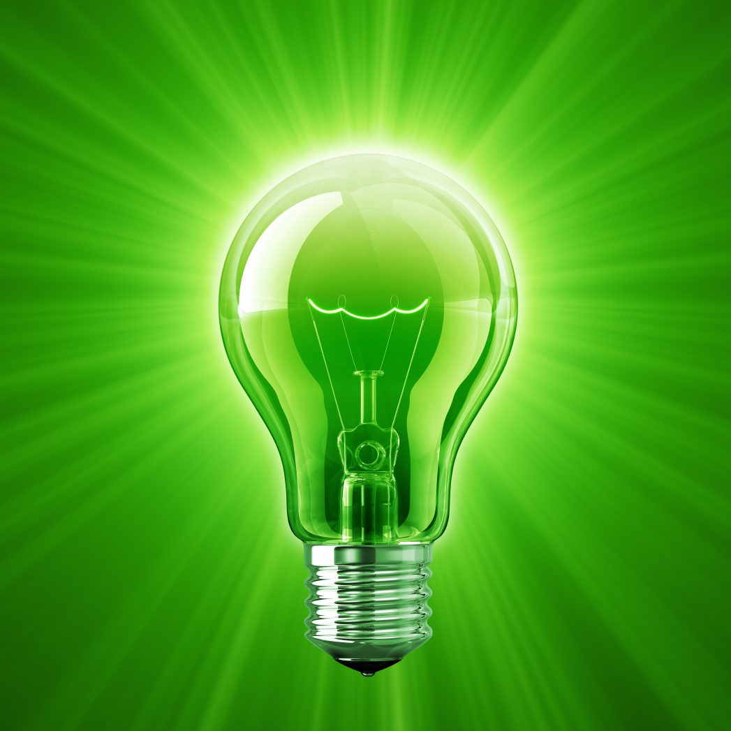 Grüne Glühbirne mit strahlendem Lichteffekt auf grünem Hintergrund.
