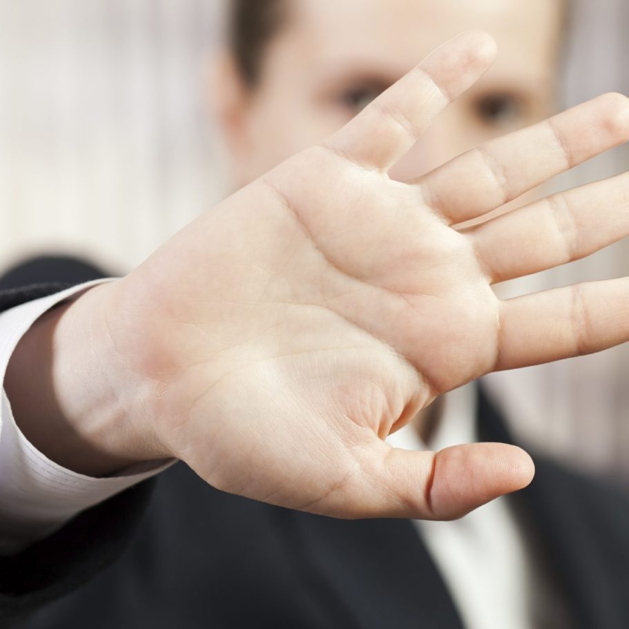 Eine Hand in einem Anzug hält mit der Handfläche sichtbar nach vorne.