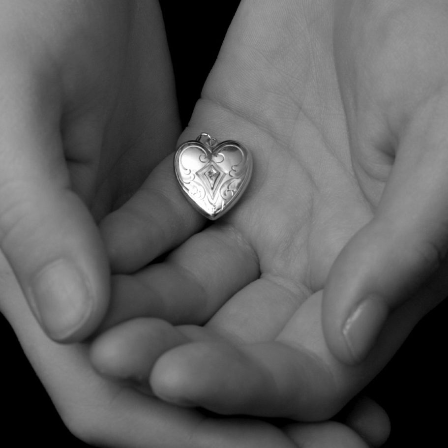 Zwei Hände halten ein kleines, glänzendes Herz.